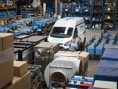 Två tekniker, en sitter på huk och en står vid en avfuktare. 