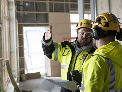 En tekniker på en byggarbetsplats som håller i en bärbar dator.